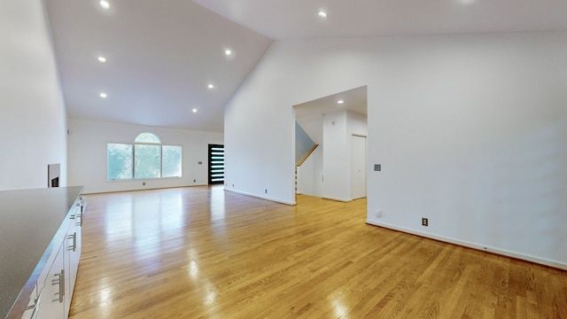 unfurnished living room with light hardwood / wood-style floors and high vaulted ceiling