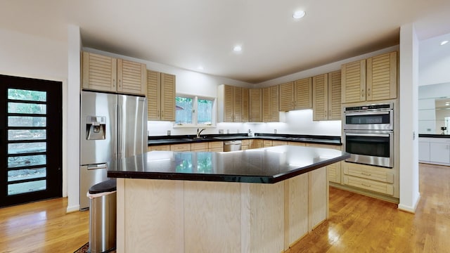 kitchen featuring appliances with stainless steel finishes, a healthy amount of sunlight, light hardwood / wood-style floors, and a kitchen island