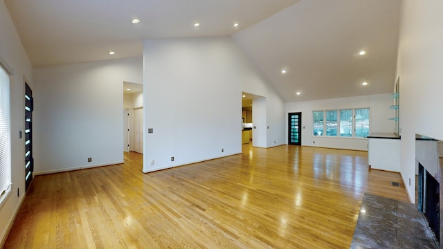 unfurnished living room with high vaulted ceiling and light hardwood / wood-style floors