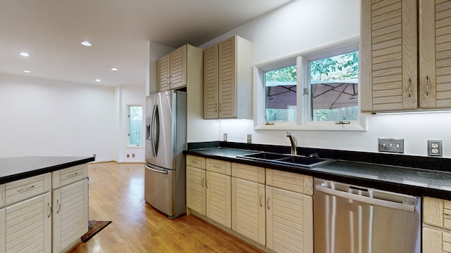 kitchen featuring cream cabinetry, stainless steel appliances, sink, and light wood-type flooring