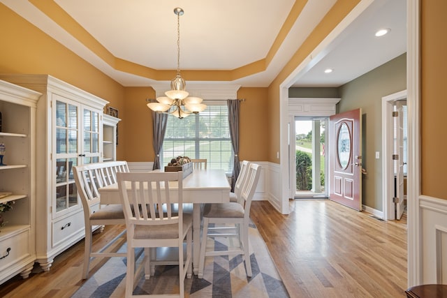 dining room featuring a chandelier, light wood-type flooring, and a raised ceiling