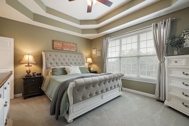 carpeted bedroom featuring a raised ceiling and ceiling fan