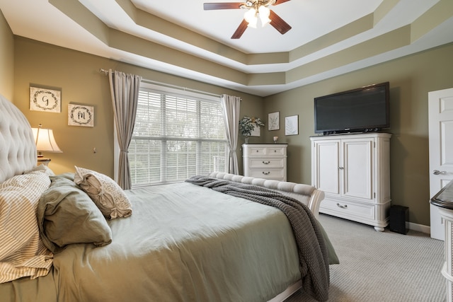 bedroom with light carpet, a raised ceiling, and ceiling fan