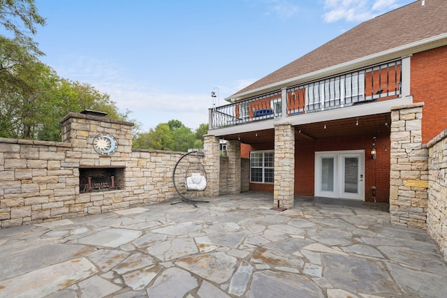 view of patio featuring a balcony and an outdoor stone fireplace