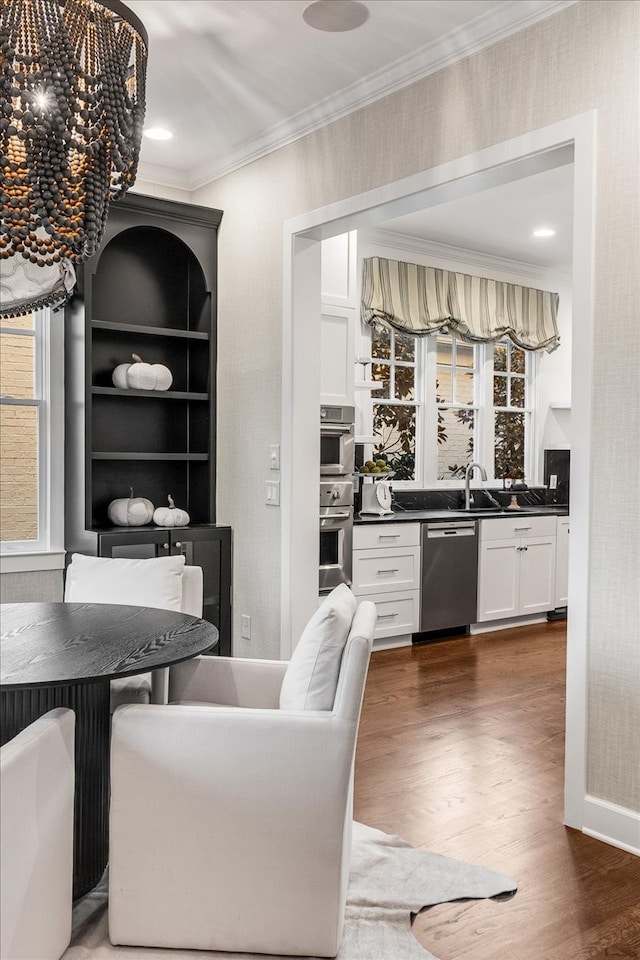 kitchen featuring sink, dark hardwood / wood-style floors, ornamental molding, white cabinetry, and stainless steel appliances