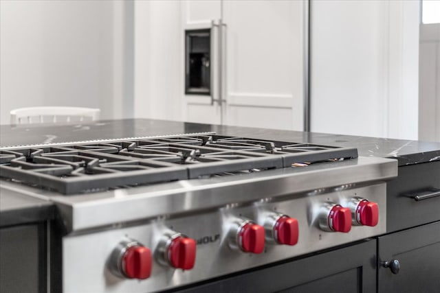 details featuring light stone counters, white cabinetry, and stainless steel range oven