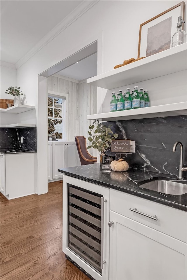 bar with dark wood-type flooring, white cabinets, crown molding, sink, and beverage cooler