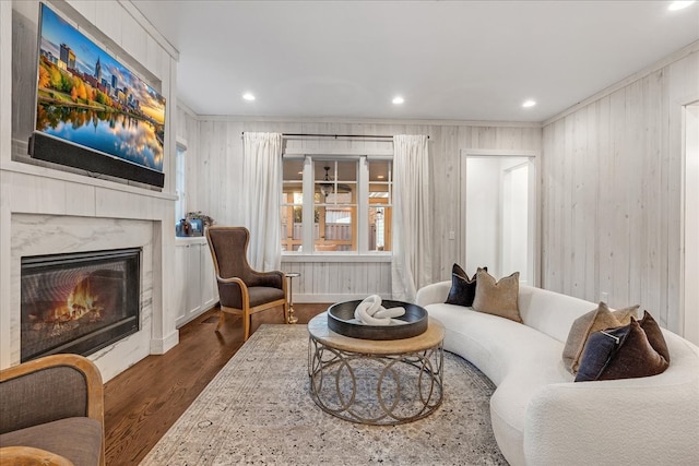 living room with ornamental molding, wooden walls, dark wood-type flooring, and a premium fireplace