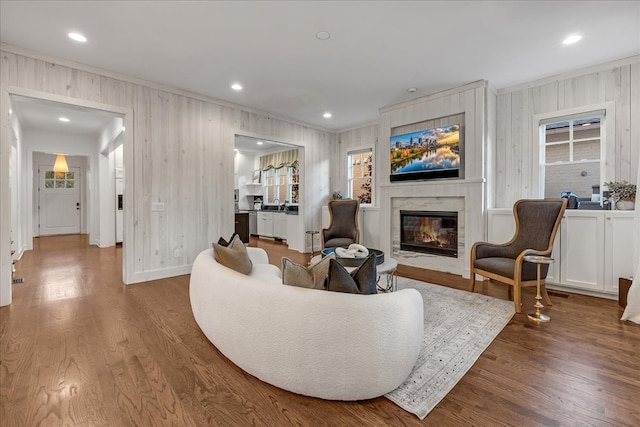 living room with hardwood / wood-style flooring, plenty of natural light, a premium fireplace, and wooden walls