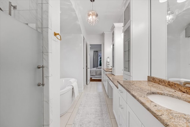 bathroom featuring tile patterned floors, vanity, a tub to relax in, and an inviting chandelier