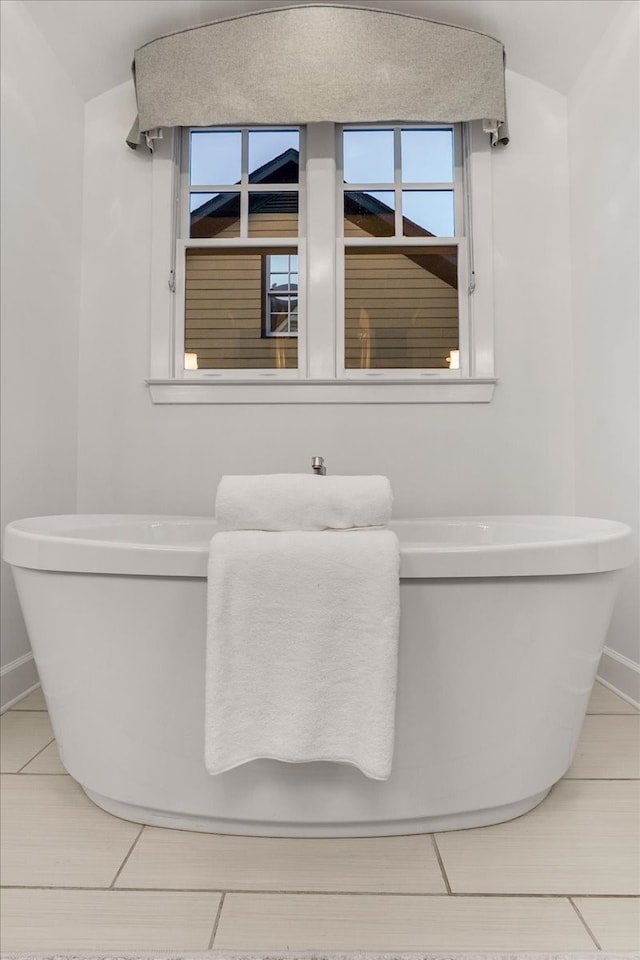 bathroom featuring tile patterned flooring, a bathtub, and lofted ceiling