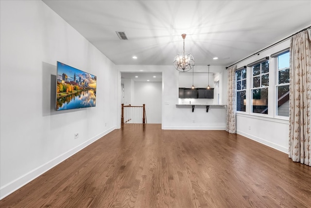 unfurnished living room featuring hardwood / wood-style flooring and a chandelier