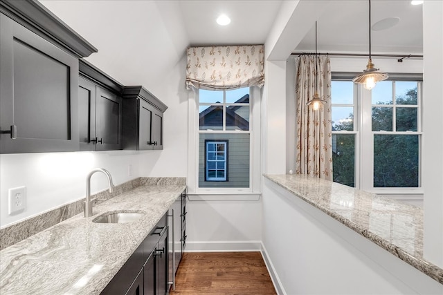 kitchen featuring light stone countertops, sink, dark wood-type flooring, and decorative light fixtures