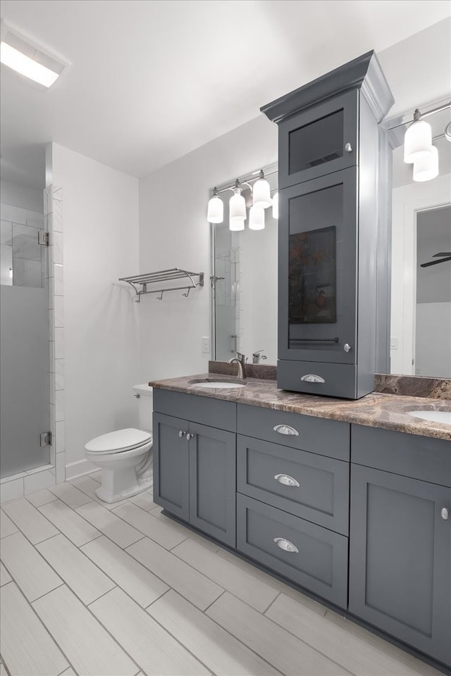 bathroom with vanity, toilet, and a shower with door