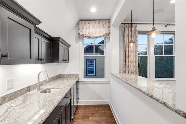 kitchen with light stone countertops, dark hardwood / wood-style flooring, decorative light fixtures, and sink