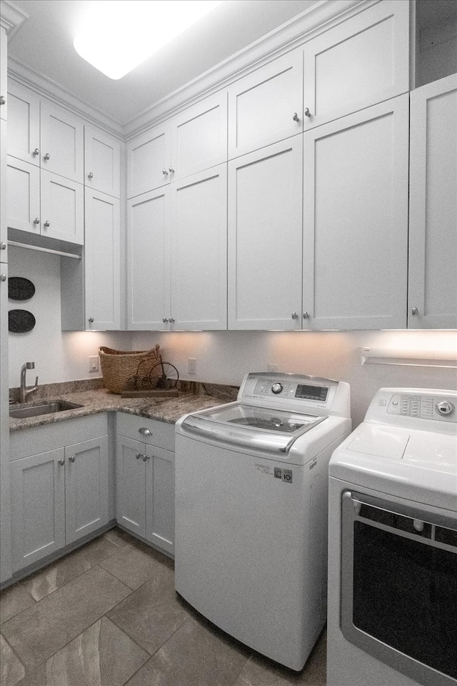 laundry room with cabinets, washing machine and dryer, dark tile patterned flooring, and sink