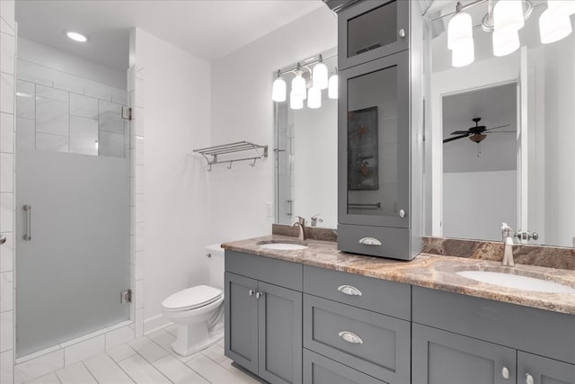 bathroom with ceiling fan, tile patterned floors, toilet, vanity, and a shower with shower door