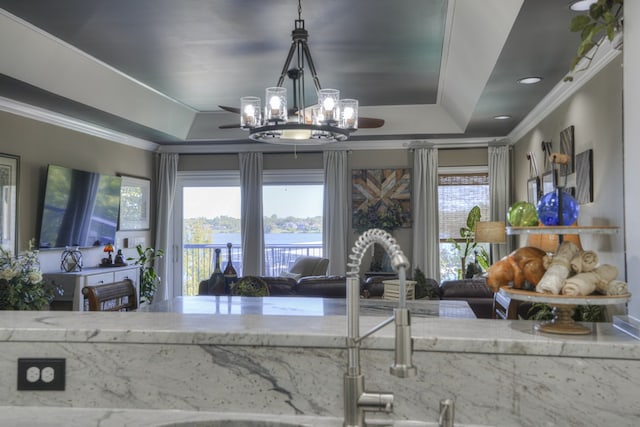 kitchen featuring ornamental molding, a tray ceiling, decorative light fixtures, and light stone counters