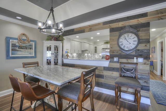 dining space with dark hardwood / wood-style floors, a chandelier, and ornamental molding