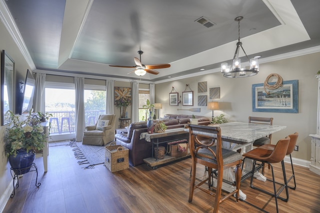 dining room featuring a raised ceiling, crown molding, and dark wood-type flooring