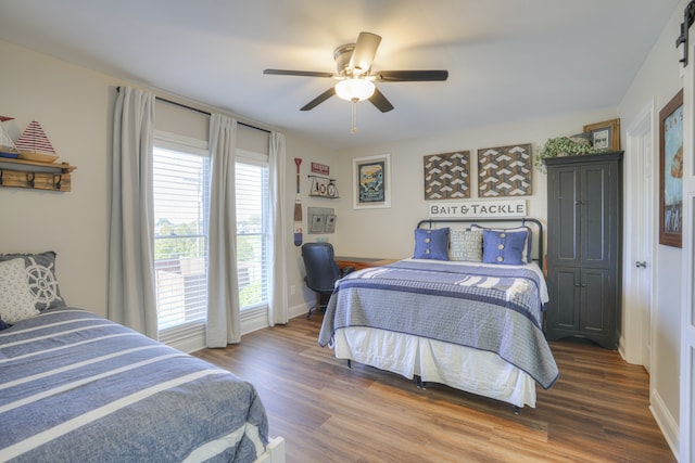 bedroom featuring ceiling fan, dark hardwood / wood-style floors, and a barn door