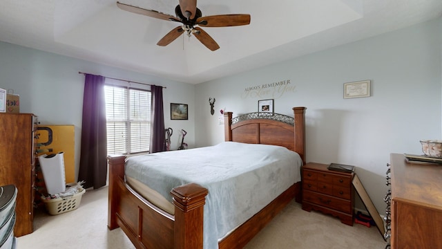 carpeted bedroom with a tray ceiling and ceiling fan