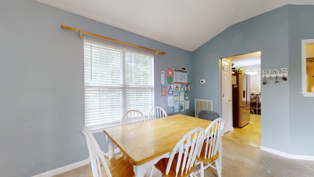 dining area with vaulted ceiling and light colored carpet