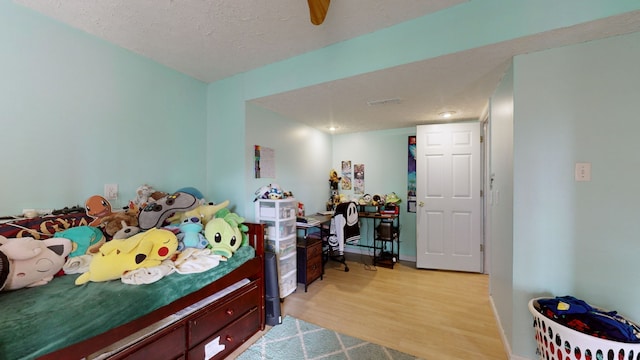 bedroom with light wood-type flooring and a textured ceiling