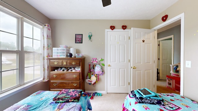 carpeted bedroom featuring ceiling fan and a textured ceiling