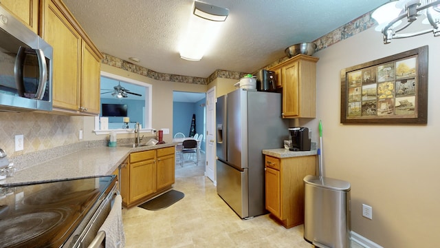 kitchen featuring hanging light fixtures, sink, a textured ceiling, appliances with stainless steel finishes, and ceiling fan with notable chandelier