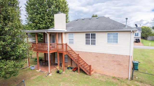 rear view of house with a lawn, a wooden deck, and a patio area