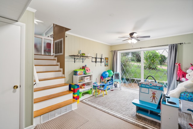 rec room featuring wooden walls, carpet, ceiling fan, and crown molding