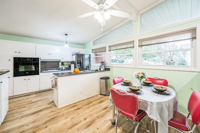 kitchen with hanging light fixtures, light hardwood / wood-style floors, white cabinetry, black oven, and vaulted ceiling with beams