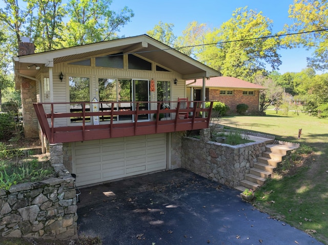 back of house featuring a wooden deck, a garage, and a lawn