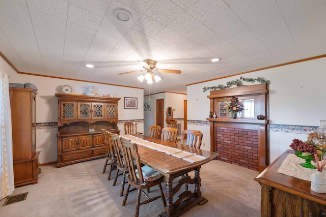 dining area featuring ceiling fan, light colored carpet, and crown molding