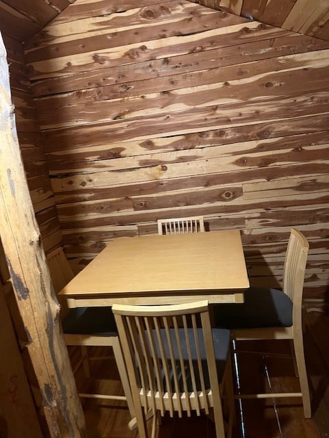 unfurnished dining area with wood walls and vaulted ceiling