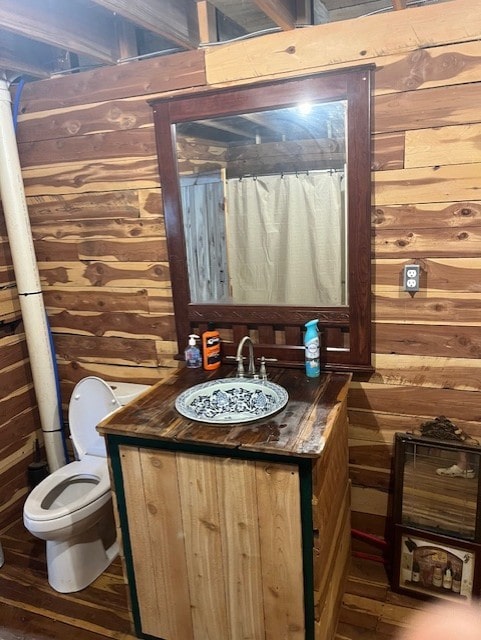 bathroom with vanity, wooden walls, toilet, and hardwood / wood-style flooring