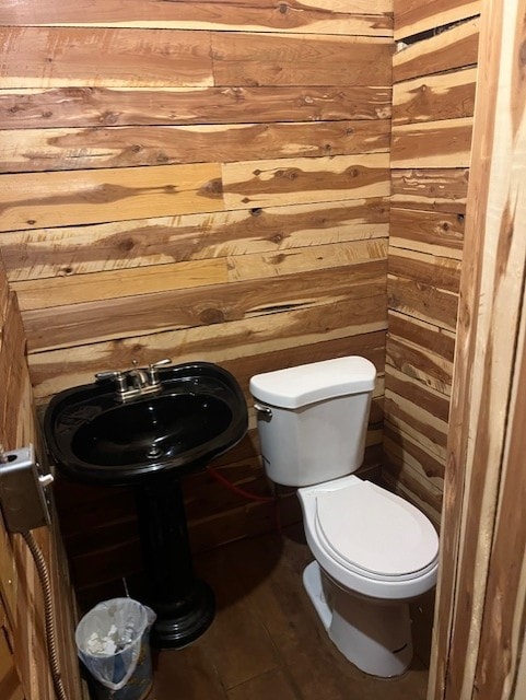 bathroom featuring wood-type flooring, wood walls, and toilet