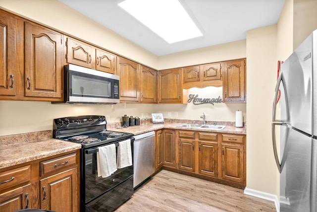 kitchen featuring stainless steel appliances, sink, and light hardwood / wood-style flooring