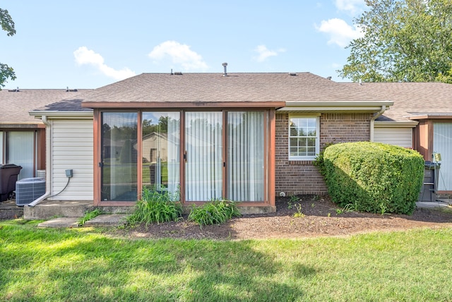 rear view of property with a lawn and central air condition unit