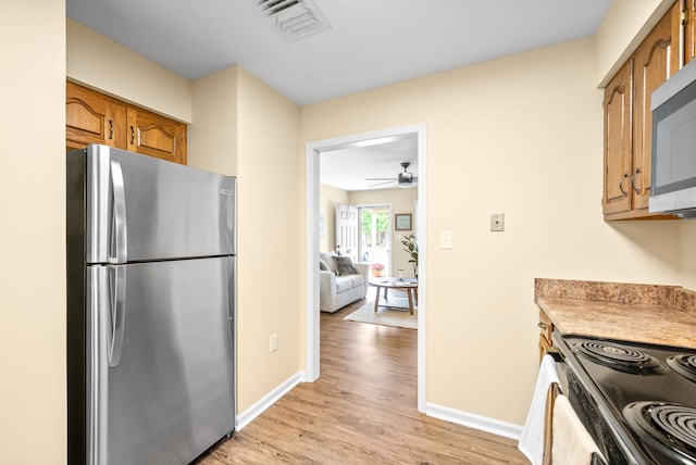 kitchen featuring ceiling fan, stainless steel appliances, and light hardwood / wood-style floors