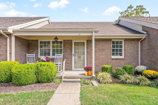 doorway to property with a yard and a porch