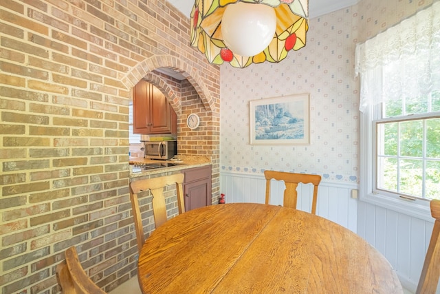 unfurnished dining area featuring wallpapered walls and a wainscoted wall