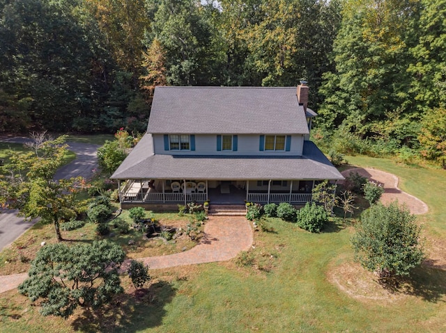 country-style home featuring a porch, a chimney, a shingled roof, and a front yard