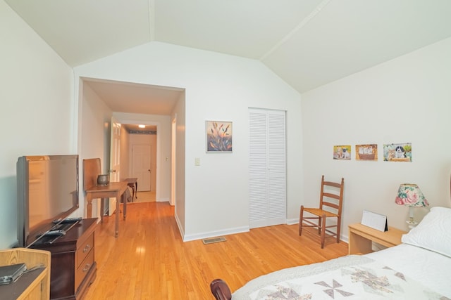 bedroom featuring visible vents, a closet, baseboards, light wood-style floors, and lofted ceiling