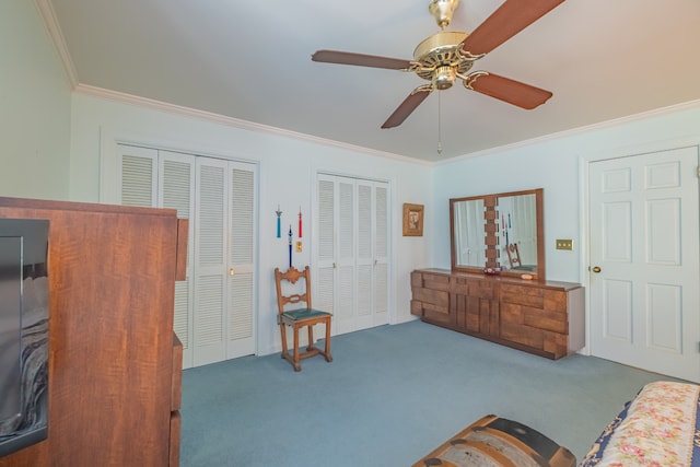 bedroom featuring two closets, ornamental molding, carpet, and ceiling fan