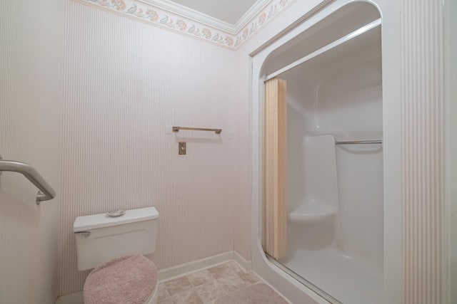 bathroom featuring toilet, a walk in shower, and baseboards