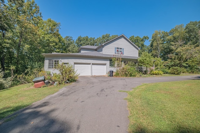 view of front of house with an attached garage, driveway, and a front lawn