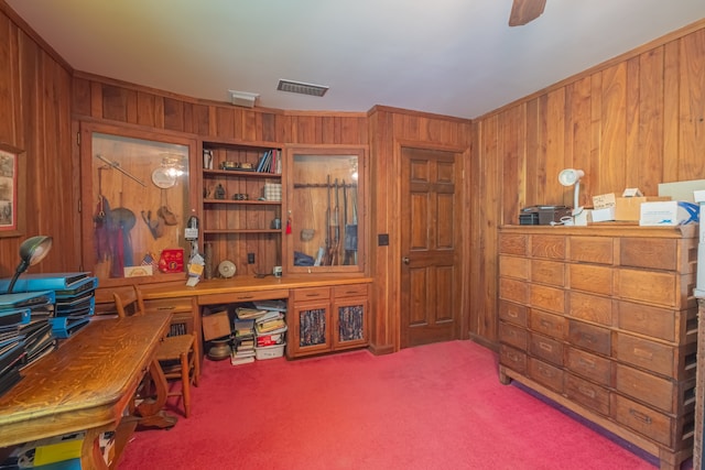 carpeted home office with ceiling fan, wooden walls, and crown molding