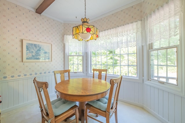 dining room with wallpapered walls, light carpet, crown molding, a wainscoted wall, and beam ceiling